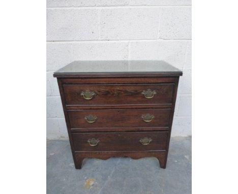 A Georgian style oak chest of three long drawers raised upon shaped bracket feet.
