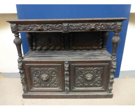 An early 20th Century Gothic style sideboard with allover carved decoration, the two lion handled drawers above a shelf and c