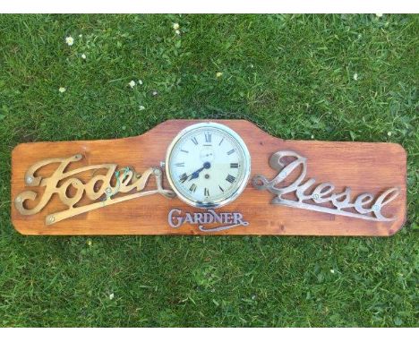 An unusual wall mounted wooden display board mounted with a Foden Diesel and Gardner insignia and central clock.