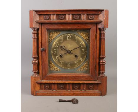 A late Nineteenth/early Twentieth century oak cased mantle clock, with carved detailing and spindle supports. The brass dial 