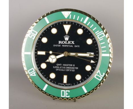 A Rolex style dealer display concessionary wall clock, "GMT Master II" gold and green bezel surround with black dial.  Quartz