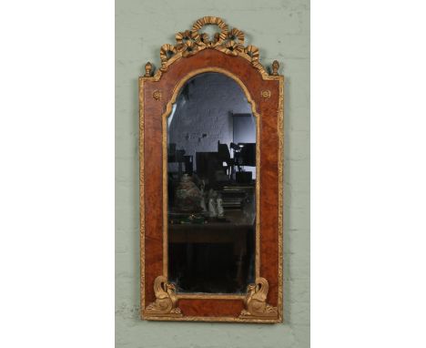 A burr walnut and gilt framed wall mirror, with arch top. Featuring mythical creatures to the bottom corners and frilled bow 