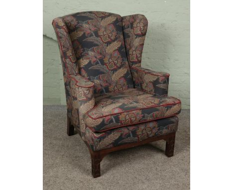 A wing back armchair in the Chippendale style. With floral upholstery and mahogany supports.Hx110cmWx84cmDx95cm