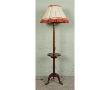A mahogany standard lamp with central platform shelf on tripod base. Height without shade 178cm.