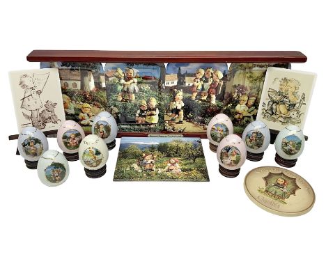 Two ceramic Hummel postcards by Goebel, both displayed on wooden easels, together nine Hummel eggs, set of four Hummel School