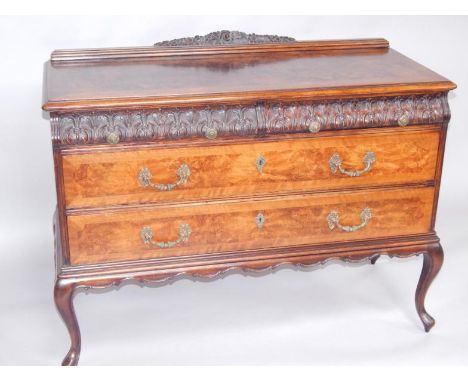 An oak and burr walnut chest, with one carved cushion and two long drawers, raised on cabriole legs, 108cm x 34.5cm x 68cm.