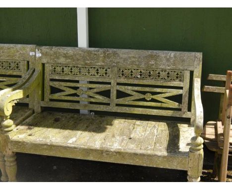 A two seater garden bench, with a pierced and carved foliate back, raised on turned legs, 131cm long.