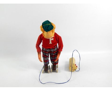 A 1960's battery operated remote control roller skating monkey, wearing a green cap, t-shirt bearing the letter F and checked