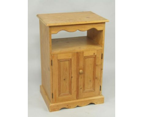 A pine bedside cupboard, with an open shelf over a cupboard raised on a plinth base, 55cm x 41.5cm x 80.5cm.