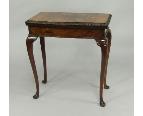 A walnut fold over card table, 20thC, the top with a ribbon and flowers head carved frieze, raised on cabriole legs, 68.5cm x