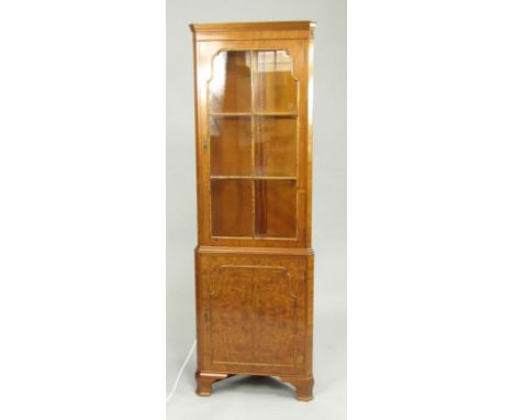 A walnut corner display cabinet, 20thC, the astragal glazed door enclosing two glass shelves, cupboard below, raised on ogee 