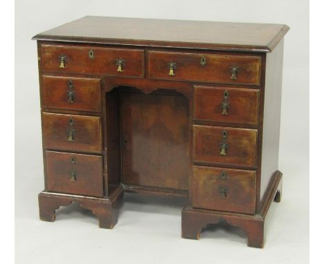 A George II walnut and cross banded kneehole desk, with two drawers above a central recessed door, flanked by six drawers, ra