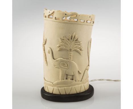 AN AFRICAN IVORY TUSK LAMP, the rim carved with a chain of elephants above a relief carving of an elephant and crocodile besi