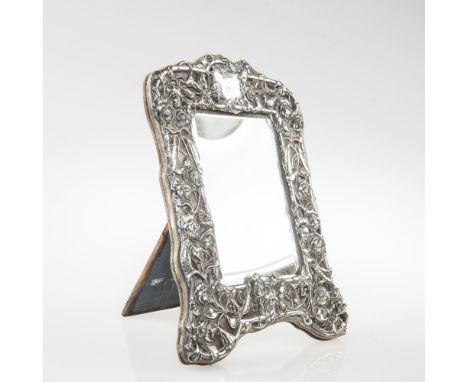 AN EDWARDIAN SILVER EASEL MIRROR, WILLIAM COMYNS, LONDON 1905, the rectangular bevelled plate within a frame decorated with b