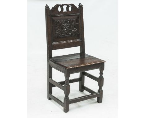 A 17th CENTURY OAK CHAIR, c.1680, with pierced and carved crest rail above a floral carved panel back over a plank seat raise