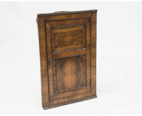 A 19th CENTURY WALNUT HANGING CORNER CUPBOARD, the moulded cornice above a fielded panel door, each of the two panels quarter