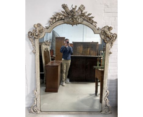 A LARGE 19TH CENTURY GILT WOOD WALL MIRROR DECORATED WITH ORNATE SCROLL WORK, FLANKED EITHER SIDE BY PUTTI WITH CENTRAL FLAMI