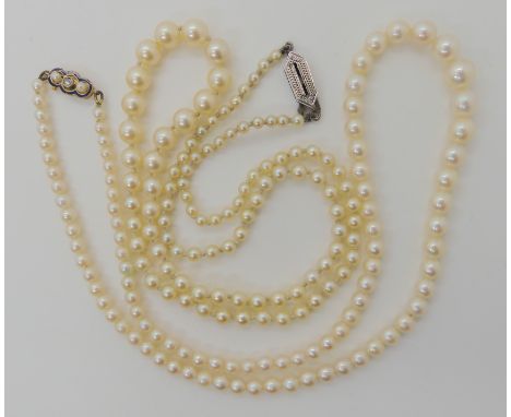 TWO STRINGS OF PEARLS WITH DECORATIVE CLASPS a string of cream pearls with good lustre, with a French 18ct gold clasp, stampe