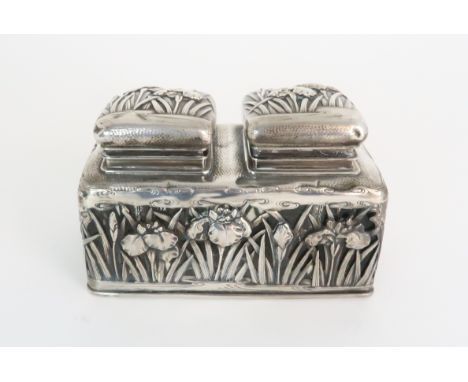 A JAPANESE WHITE METAL DOUBLE INKWELL cast with irises and set with two hinged covers above a glass encased box, stamped, Art