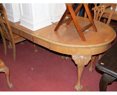 An early 20th century faded walnut dining suite comprising; extending dining table with wind-out action and three extra drop-