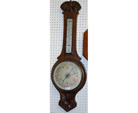 A mid-20th century low relief carved oak aneroid two-dial wheel barometer