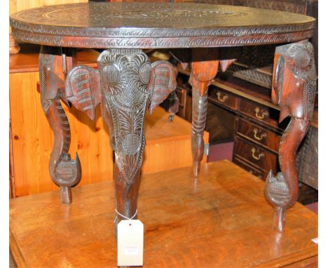 An early 20th century Indian low relief carved teak oval low occasional table, carved with central deity within standing elep