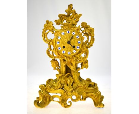 A 19th century French Rococo Revival ormolu mantel clock of profusely scrolling design, the gilt dial with enamel chapters in