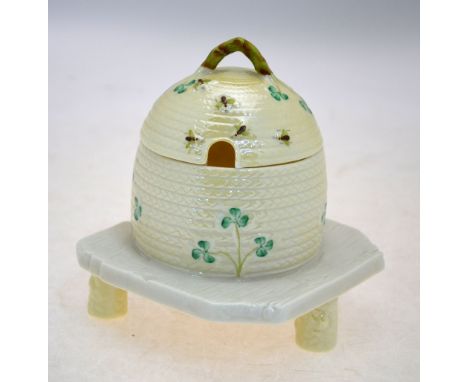 A Belleek honey pot or condiment jar with domed cover and loop handle finial, designed as a bees nest; on square base with tr