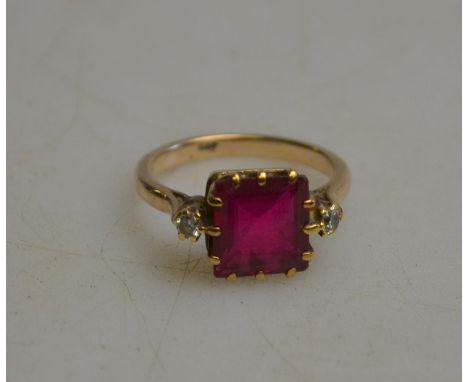 A square synthetic ruby ring having a small diamond on either side, yellow metal claw setting stamped 9ct