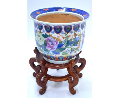 A famille rose and underglaze blue decorated planter; the base with six-character mark; with wood stand, 36 cm. diameter (2) 
