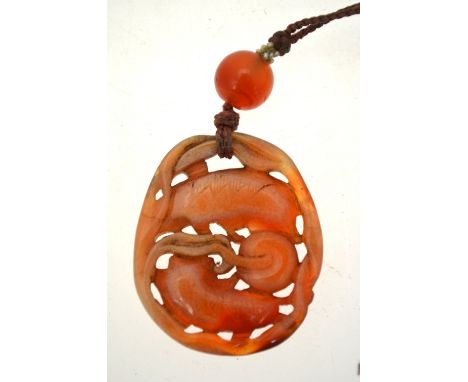 A Chinese chalcedony pendant carved with two dogs playing with a brocade ball, 42 mm long, 19th century