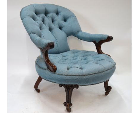 A Victorian mahogany framed button upholstered easy open armchair with scroll arm detail, raised on moulded front legs to cer