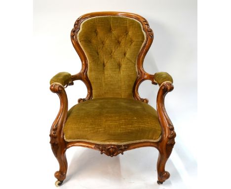 A Victorian walnut framed button upholstered spoon back open armchair raised on moulded cabriole front legs to brass castors