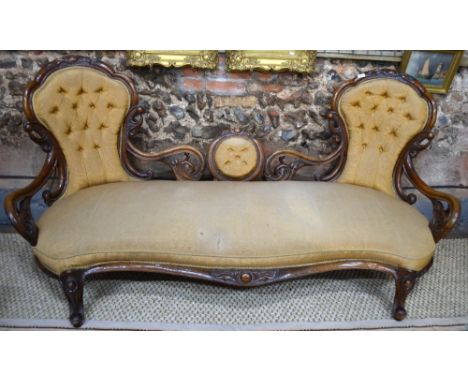 A Victorian mahogany carved and moulded framed sofa having arched chairback ends united by an oval panelled centre over an ov