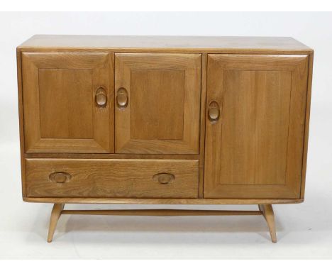 A 1960s Ercol blond elm 'Windsor' model 366 compact sideboard, having an arrangement of three cupboard doors, and single lowe