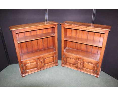 Pair of oak open bookcase, each with a single shelf above two panelled cupboard doors, on block feet, 83.5cm wide