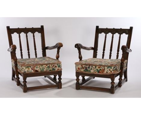 Two Ercol dark stained armchairs, with carved gothic arch backs, shaped arms on turned supports, on turned legs and flattened