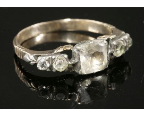A Georgian paste set ring,  HBwith a cushion-shaped colourless paste set at the centre, in a silver cut down collet with a fl