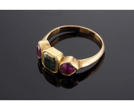 An Indian high carat gold, emerald and ruby three stone ring,with an emerald cut emerald, rub set to the centre.  An oval fac