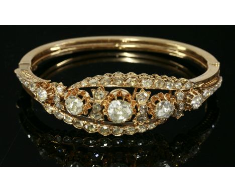A Victorian diamond set gold hinged bangle,with a crossover centrepiece composed of five graduated Dutch rose cut diamonds, a