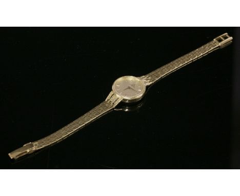 A ladies' 18ct gold Omega quartz bracelet watch,with a pinstripe champagne dial, raised gold batons and sword hands.  An inte