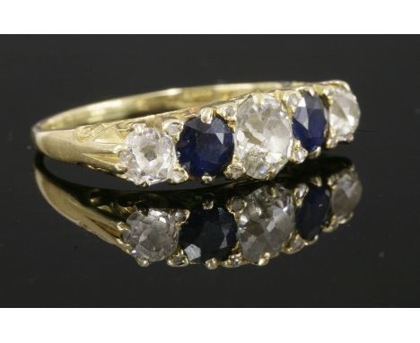 A late Victorian five stone diamond and sapphire carved head ring,with an old European cut diamond to the centre.  A circular