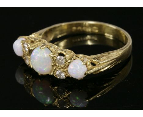 An 18ct gold, opal and diamond ring,with three circular cabochon opals, claw set between pairs of brilliant cut diamonds, Lon