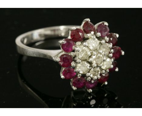 A white gold diamond and ruby cluster ring,with a central cluster of seven brilliant cut diamonds, surrounded by an outer row