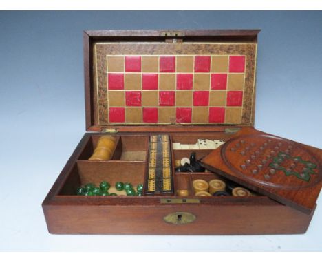 A VINTAGE WOODEN GAMES BOX AND CONTENTS, the contents to include miniature bone dominoes, chess and chequer pieces, pegboard,
