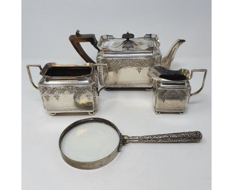 A magnifying glass, with a silver colour metal handle, a silver plated three piece tea service, an oval tea caddy and a silve