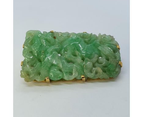 A carved jade brooch, in yellow metal mount47mm by 22mm a deepest point, 6.2 mm deep, 19.4 g no visible faults to the naked e