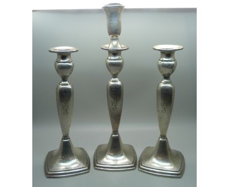 A pair of silver candlesticks and one matching taller, all with engraved initials 