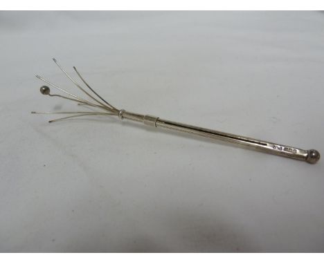 A silver swizzel stick / cocktail stirrer engine turned decoration, the push slide revealing seven stamens the central prong 