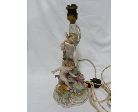 A German porcelain candlestick lamp base, of Sitzendorf type, modeled as two putto playing against a foliate stump with appli